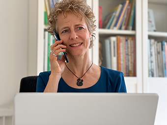 Irene de Groot, grafisch ontwerper, aan de telefoon achter een laptop